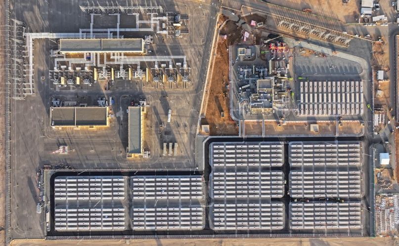 Complete aerial view of a grid-connected battery energy storage system beside high-voltage substation equipment