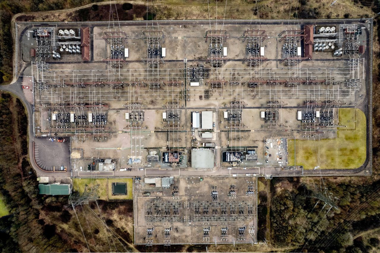 Complete aerial view of a high-voltage grid station with busbars, transformer bays and switchyard equipment